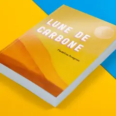 Livre de poche "Lune de Carbone" de Madeline Anagnos, sur fond jaune et bleu. La couverture présente un dégradé orangé et un cercle blanc.