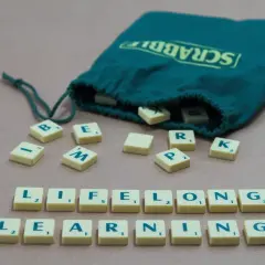Des tuiles Scrabble forment les mots "LIFELONG LEARNING", illustrant un exemple de langage soutenu.