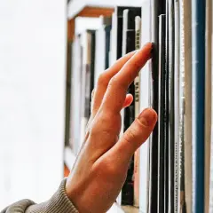 Main d'une personne effleurant une étagère remplie de livres, un voyage au cœur de la classique littérature.