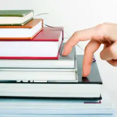 Main qui progresse sur une pile de livres, comme pour imprimer son roman.
