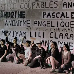 Des femmes s'agenouillent devant un mur couvert de noms, dont "Anonyme", peut-être en soutien à une écrivaine anonyme.