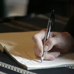 Main d'une personne écrivant à la main dans un carnet, peut-être pour des **éditions pol manuscrit**.
