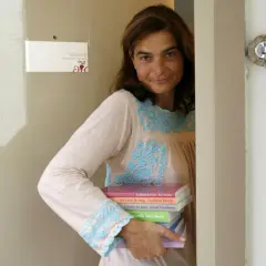 Héloïse d'Ormesson, souriante, tient une pile de livres. Sur le mur, une carte "Éditions Héloïse d'Ormesson".
