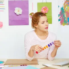 Jeune femme cherchant comment trouver l'inspiration pour écrire, entourée de couleurs vives et de fleurs.