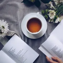 Un thé, des fleurs et un livre ouvert, un moment de calme propice à la réflexion sur le lieu d'édition d'un livre.