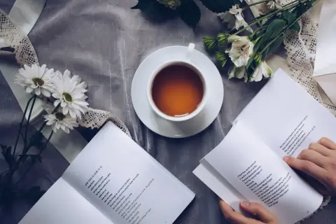 Un thé, des fleurs et un livre ouvert, un moment de calme propice à la réflexion sur le lieu d'édition d'un livre.