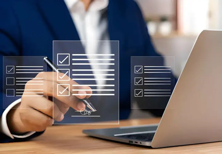 Un homme en costume signe un document numérique, validant un bon à tirer exemple. Des listes de contrôle virtuelles apparaissent sur des écrans transparents.