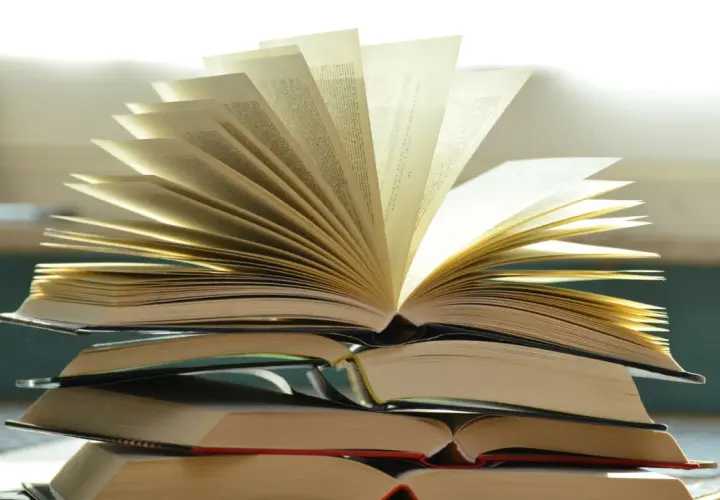 Pile de livres ouverts, pages déployées comme un éventail, évoquant la richesse du savoir et la quête spirituelle. Une maison d'édition spiritualité qui ouvre les portes de la connaissance.