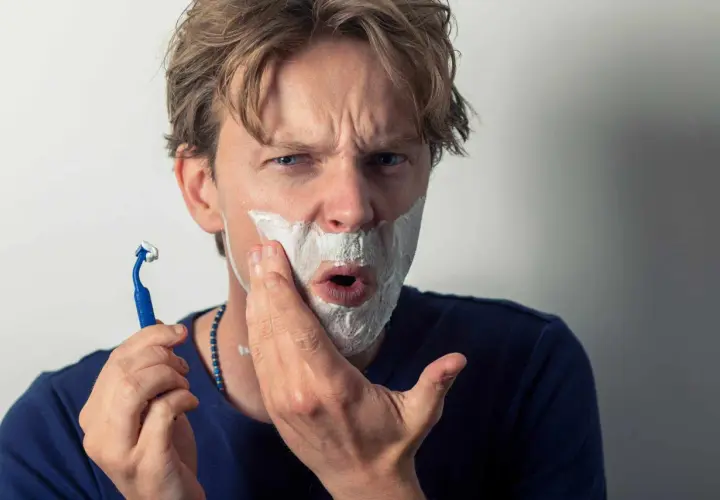 Un homme se rase, la mousse envahit sa bouche comme une figure de style pour exagérer son expression de surprise.