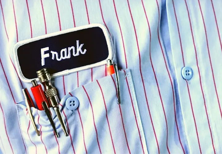 Chemise à rayures bleues et rouges avec un badge "Frank" et des stylos dans la poche. Le titre du roman est le nom du personnage principal.