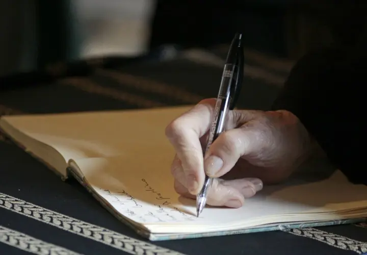 Main d'une personne écrivant à la main dans un carnet, peut-être pour des **éditions pol manuscrit**.