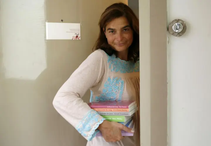 Héloïse d'Ormesson, souriante, tient une pile de livres. Sur le mur, une carte "Éditions Héloïse d'Ormesson".