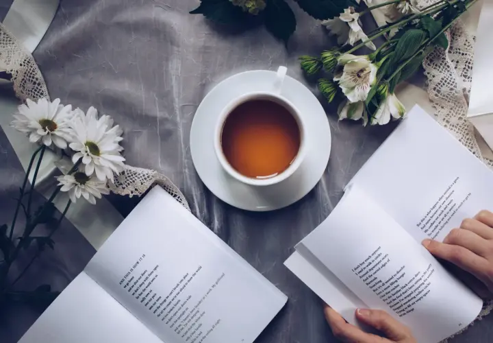 Un thé, des fleurs et un livre ouvert, un moment de calme propice à la réflexion sur le lieu d'édition d'un livre.