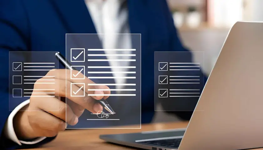 Un homme en costume signe un document numérique, validant un bon à tirer exemple. Des listes de contrôle virtuelles apparaissent sur des écrans transparents.