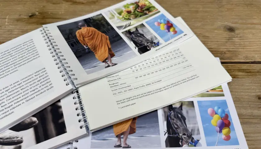 Livre broché : moine en orange, cheval noir, ballons colorés. Spécifications techniques du papier, dont le grammage 200g.
