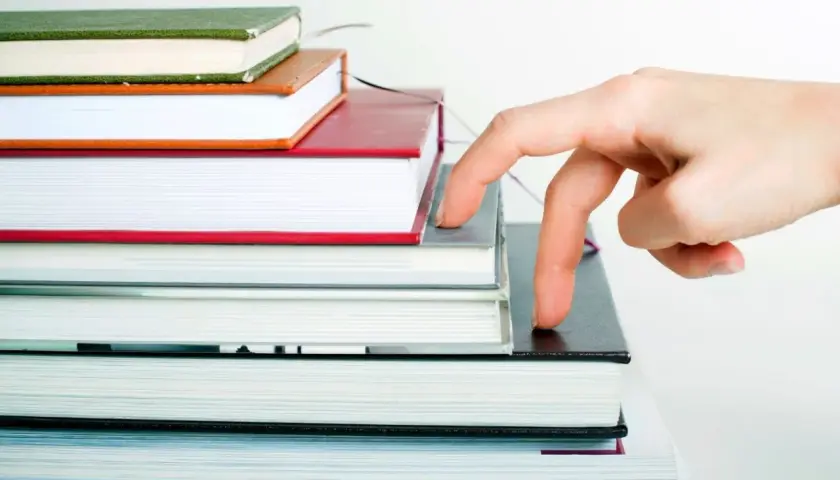 Main qui progresse sur une pile de livres, comme pour imprimer son roman.