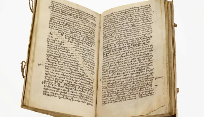 Page de manuscrit ancien avec des lignes de texte manuscrit en latin. Le livre est ouvert, révélant deux pages remplies d'écriture.
