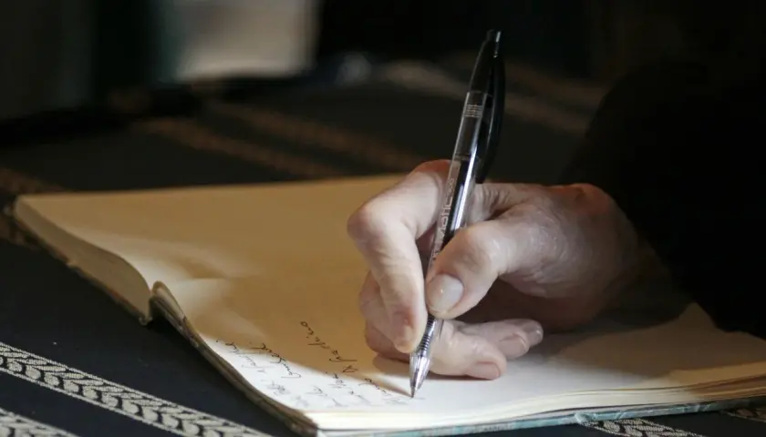 Main d'une personne écrivant à la main dans un carnet, peut-être pour des **éditions pol manuscrit**.