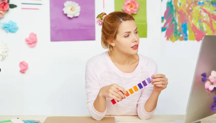 Jeune femme cherchant comment trouver l'inspiration pour écrire, entourée de couleurs vives et de fleurs.