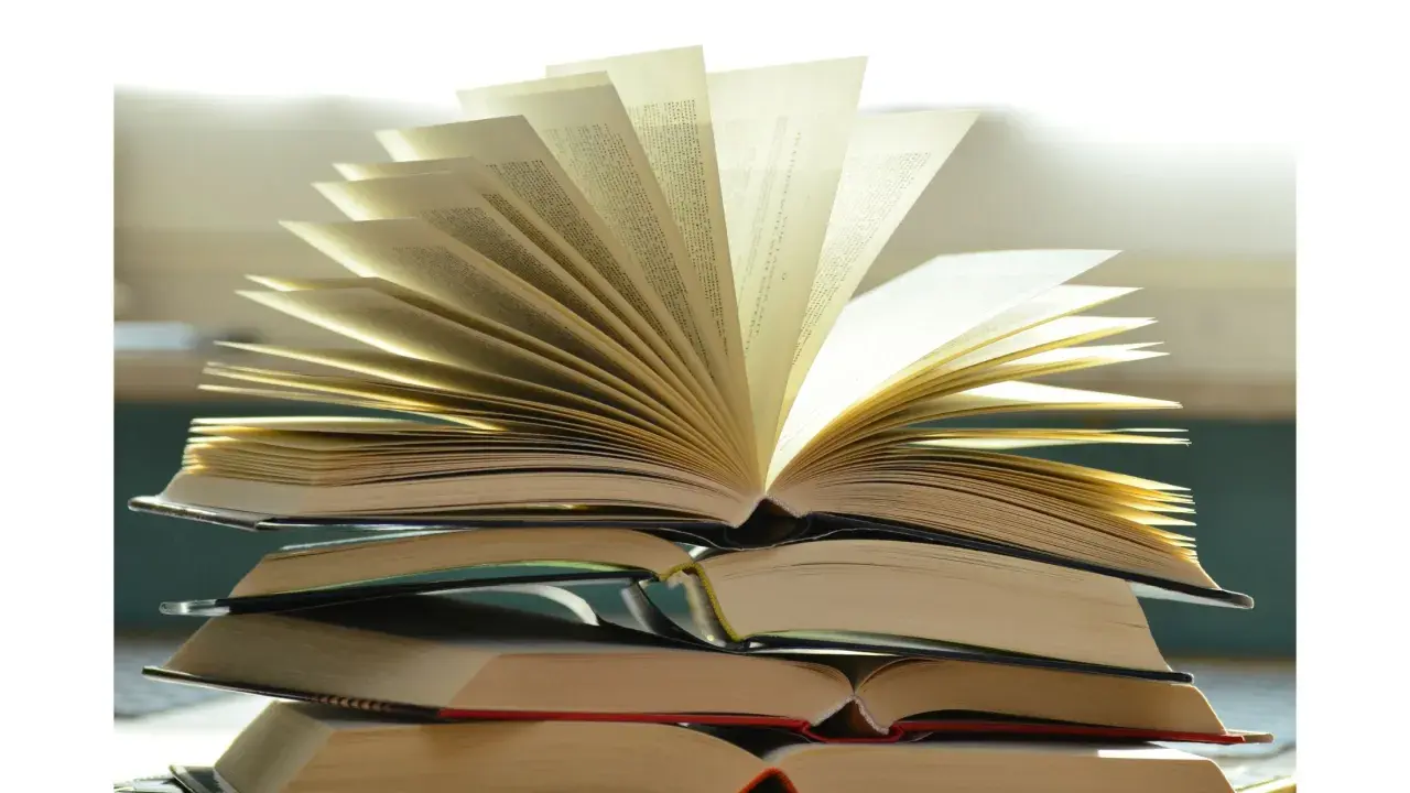 Pile de livres ouverts, pages déployées comme un éventail, évoquant la richesse du savoir et la quête spirituelle. Une maison d'édition spiritualité qui ouvre les portes de la connaissance.