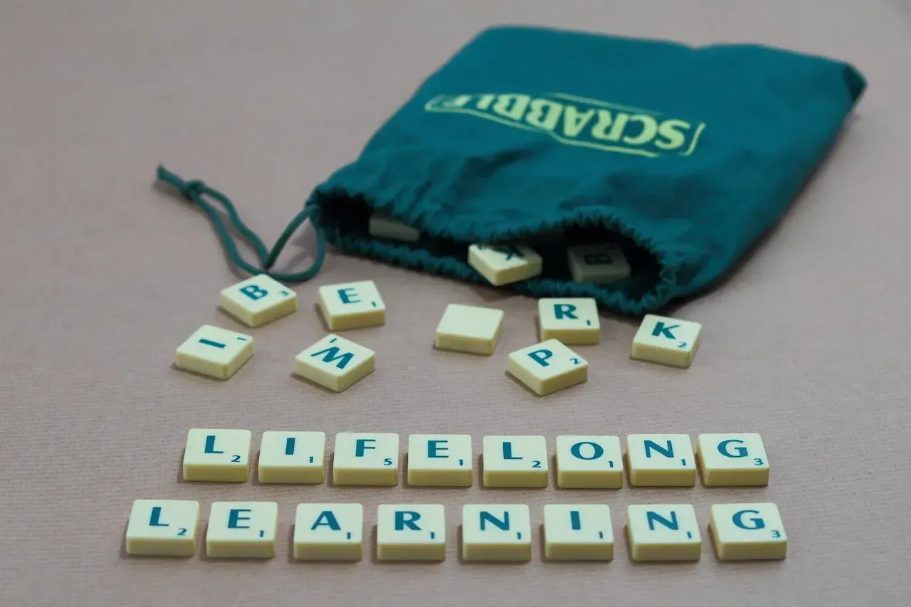 Des tuiles Scrabble forment les mots "LIFELONG LEARNING", illustrant un exemple de langage soutenu.