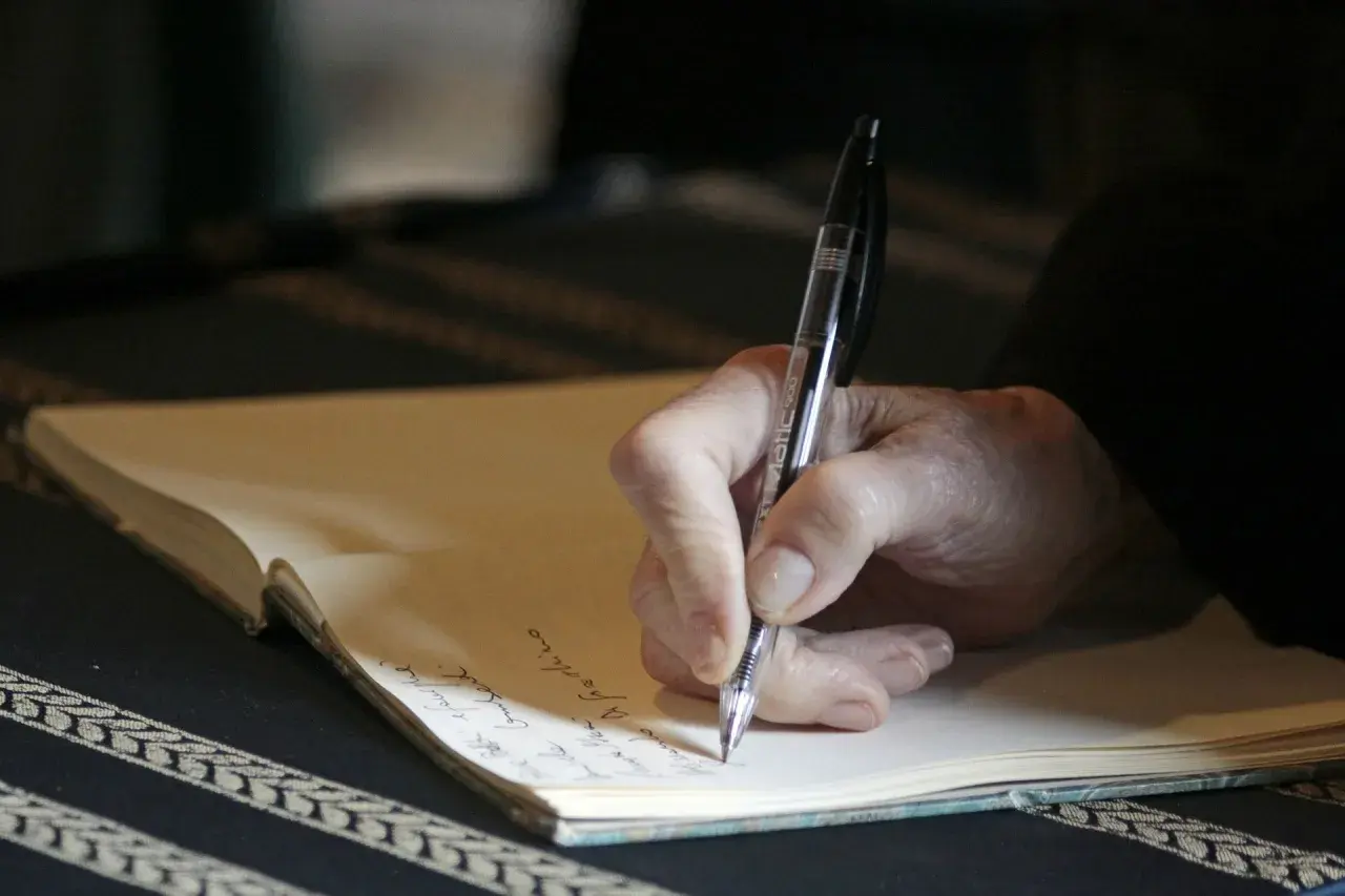 Main d'une personne écrivant à la main dans un carnet, peut-être pour des **éditions pol manuscrit**.
